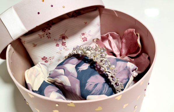 Rosa Geschenkbox mit dekorativen Kissen und Blüten aus Stoff.